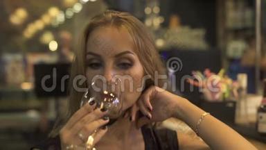 当女人在餐馆里喝酒时，从酒杯里喝红酒。 参加活动的女士喝红酒